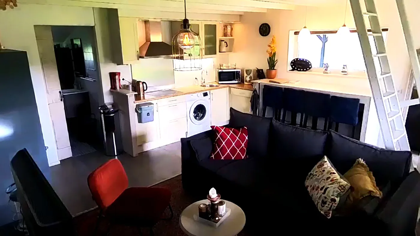 Living area with køkken, sofa and stairs to the sovehems.
